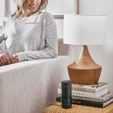Black | Woman smiles while looking at the Homedics TotalClean 4-IN-1 UV Portable Air Purifier in black on end table