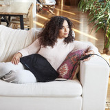 Woman sits in couch with the Homedics 12" x 24" Weighted Gel Heating Pad spread across her lap